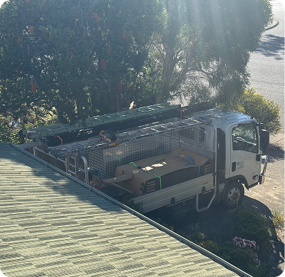 Work truck with ladders parked beside the roof